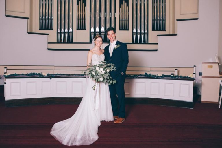 smiling couple posing in front of organ